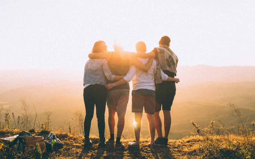 A family standing together outdoors looks out toward the sun