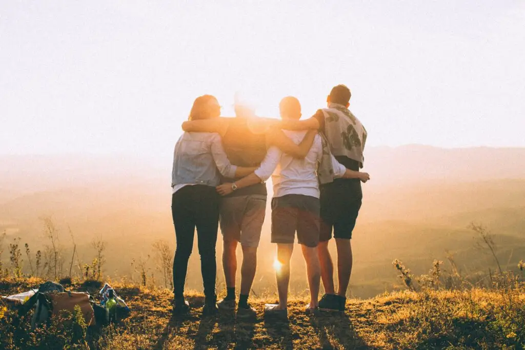 A family standing together outdoors looks out toward the sun