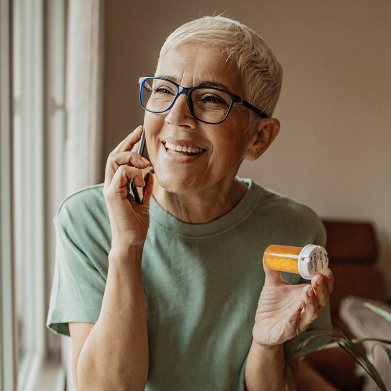 member-medication A female Medicare member uses the Pyx Health app while sitting on a sofa.