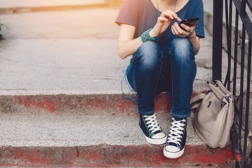 Young adult sitting on steps using a mobile phone