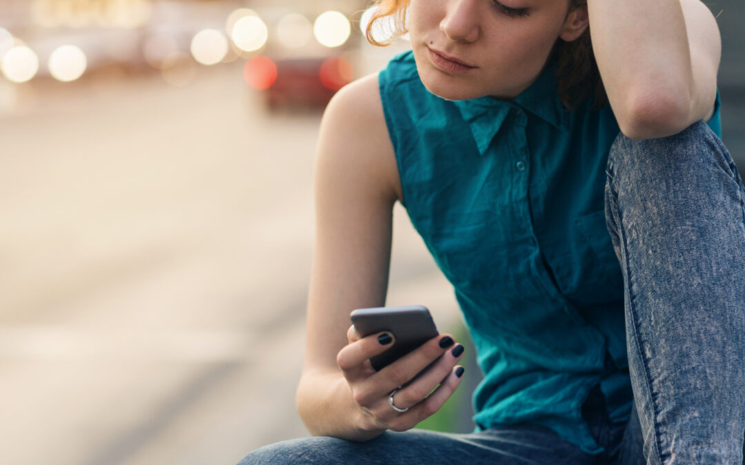 A young adult sitting alone using a smart phone