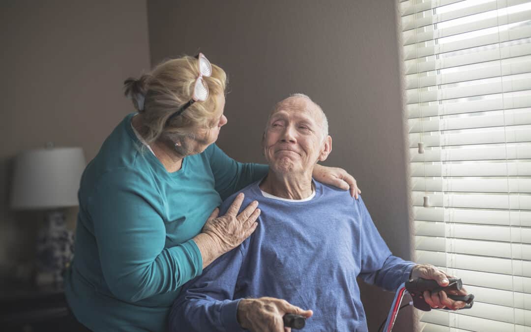 A caregiver provides support for an elderly man